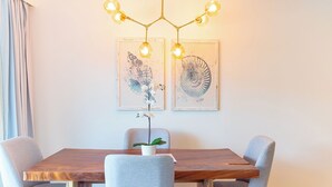 A dining area with a wooden table, four grey chairs, a potted orchid, and two wall-mounted artworks depicting shells. - Lifestyle Holidays Vacation Club - Presidential Suites - 1 Bedroom suite (Cabarete)