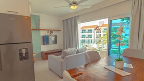 A modern living room with a sofa, a dining table with a plant, and a TV on the wall. - Lifestyle Holidays Vacation Club - Presidential Suites - 1 Bedroom suite (Cabarete)
