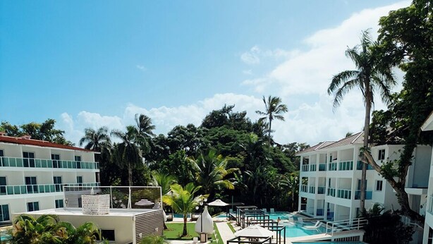 A pool area with sun loungers and a separate swimming pool, surrounded by greenery and buildings. - Lifestyle Holidays Vacation Club - Presidential Suites - 1 Bedroom suite (Cabarete)