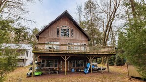 A wooden cabin with a balcony, a fire pit, and a covered deck area. - Lake House On Sweet Arrow Lake (Pine Grove)
