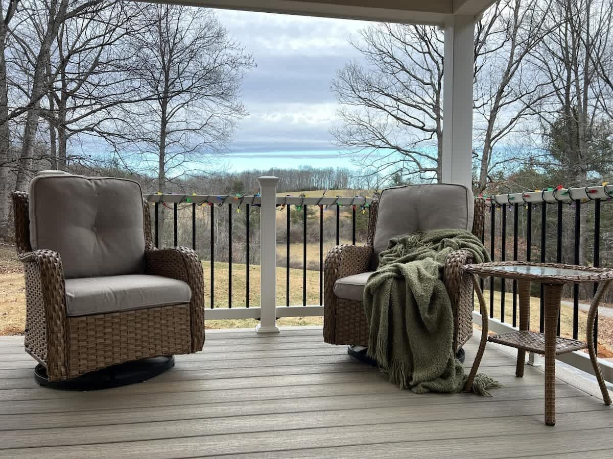 A covered outdoor seating area with wicker chairs and a small table.