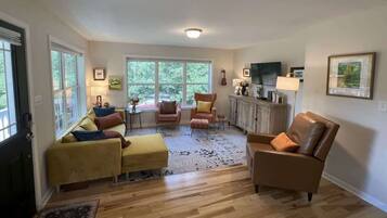 A spacious living room with a sofa set, a brown leather armchair, and a coffee table.