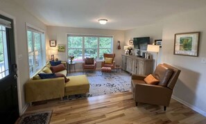 Un salón amplio con un conjunto de sofás, un sillón de cuero marrón y una mesa de centro.