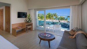 Ein Hotelzimmer mit Balkon, Fernseher, einer hölzernen Bank, einem kleinen Tisch und einem Sofa.