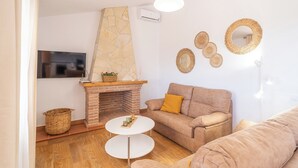Un salon chaleureux avec une cheminée en briques, un canapé beige, une table basse ronde et des miroirs décoratifs fixés au mur.
