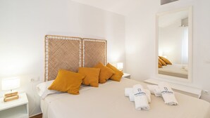 Une chambre d’hôtel comprenant un lit, deux tables de chevet, un miroir et une tête de lit ornée d’un motif tissé.