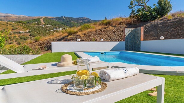 Un espace piscine offrant une vue dégagée sur le paysage environnant, notamment sur les collines et un village situé au loin.