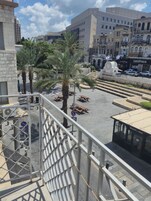 A public square with palm trees, benches, and a bakery.