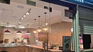 Un restaurant appelé « Cheezy Pizza », doté d’un intérieur moderne et d’une enseigne indiquant qu’il sert des pizzas et de la bière.