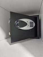 Un control remoto blanco en una caja negra con un manual de instrucciones claro.