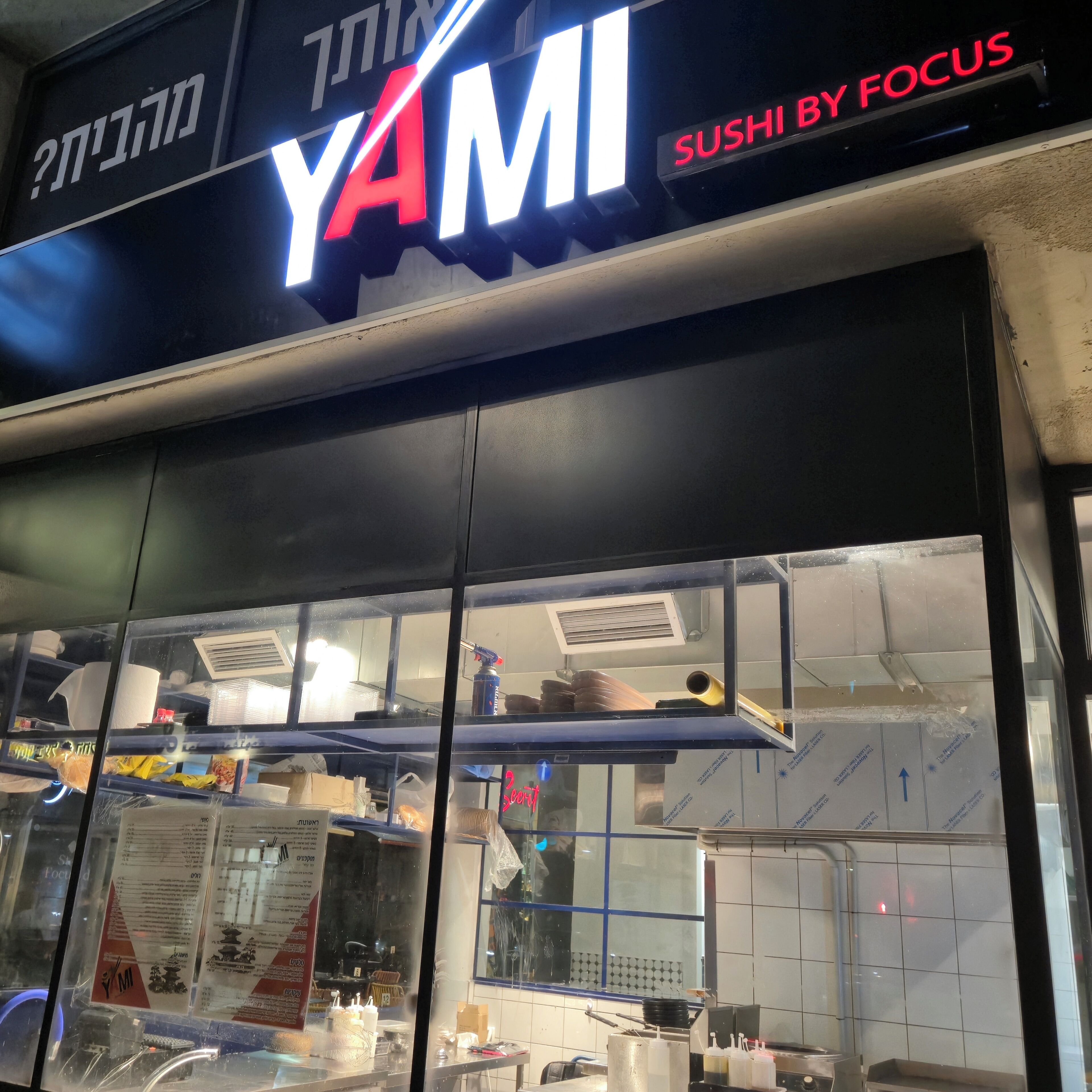 A sushi restaurant named YAMI with a neon sign.