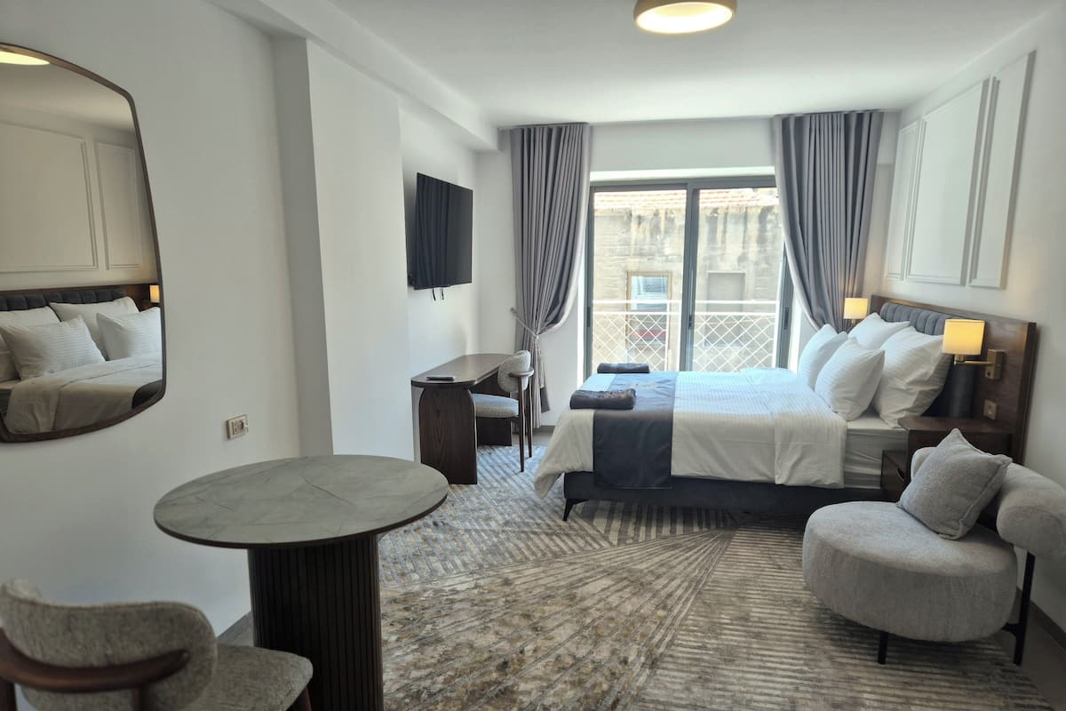 Una habitación de hotel con cama, escritorio, silla, mesa redonda y un espejo grande.
