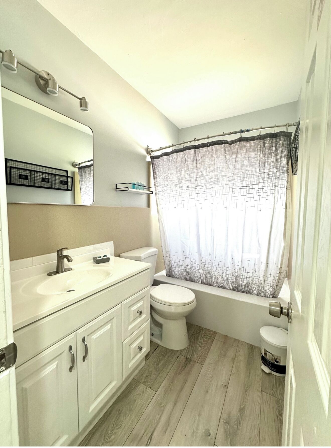 A bathroom with a white sink, mirror, toilet, and bathtub.