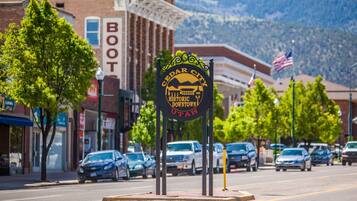 Señal de calle para el centro histórico de Cedar City, Utah, con automóviles estacionados a lo largo de la calle y edificios al fondo.