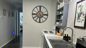 A modern kitchen with a central island, stainless steel appliances, and a wall clock. - Hidden Gem Quiet 2BR Guest House Near Downtown with King Beds, Kitchen & Patio (Natchitoches)