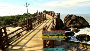 A wooden boardwalk leading to a beach with a sign promoting nature preservation. - Hotel Vila Águamar (Itapoá)
