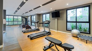 A modern gym with treadmills, a bench, and exercise balls.