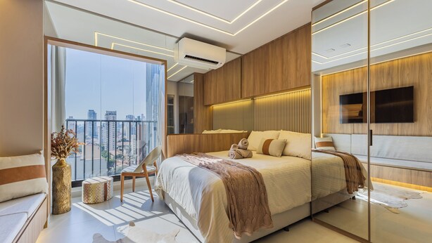 A modern bedroom with a large bed, a view of the city, and a mounted TV.