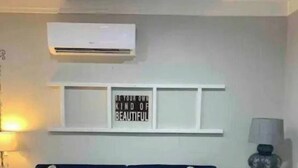 A living room with a blue sofa, a small table, an air conditioner, and a wall with a motivational quote. - Cottage Suite 3 in Fort Payne (Fort Payne)