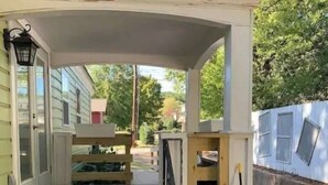 A wooden staircase leading to a covered porch with a railing, a small table, and a potted plant. - Cottage Suite 3 in Fort Payne (Fort Payne)