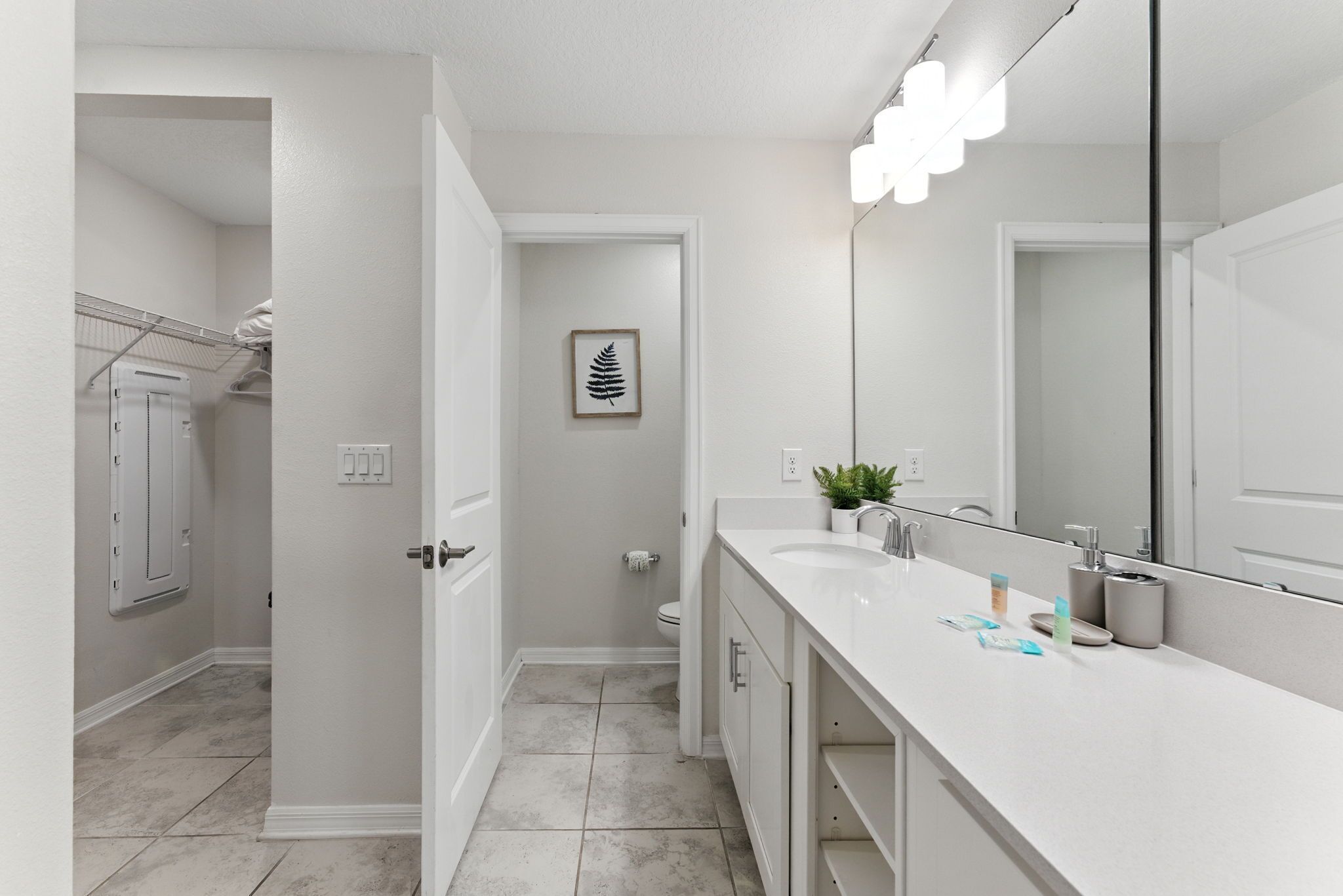 Une salle de bain moderne avec un grand miroir, un meuble-lavabo blanc et un espace douche.