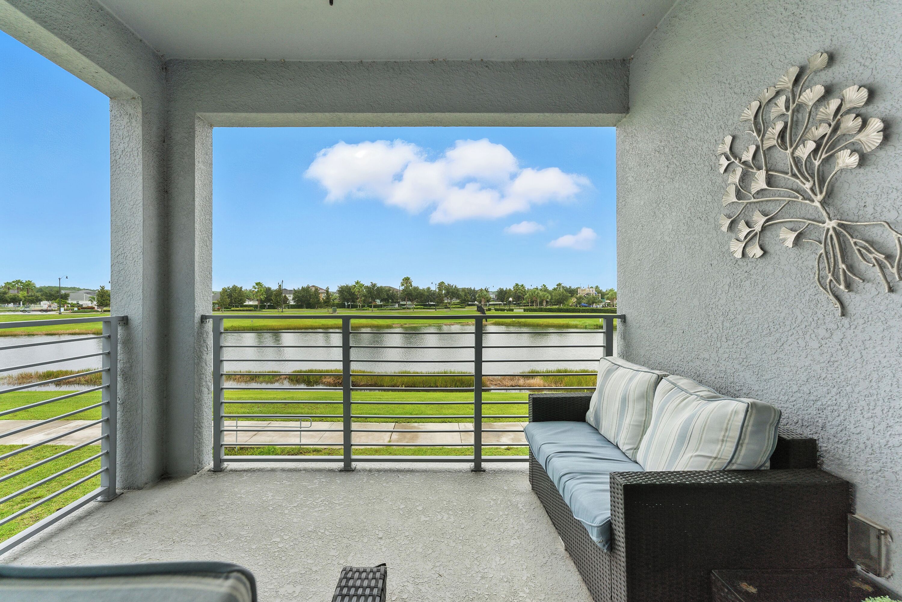 A balcony with a view of a green landscape and a clear sky.