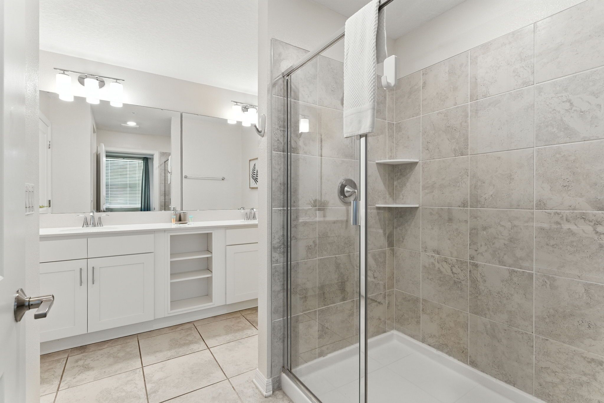 Une salle de bain moderne avec une douche à parois de verre, des meubles blancs et un grand miroir.