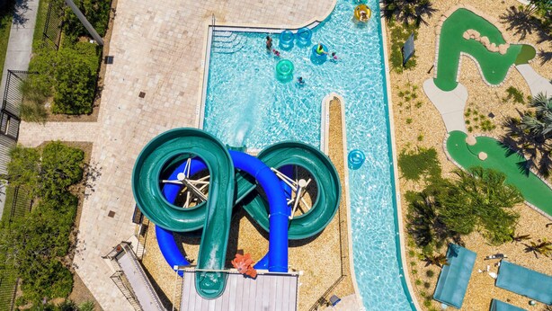 Vista aérea de una zona de piscina con tobogán y jardines.
