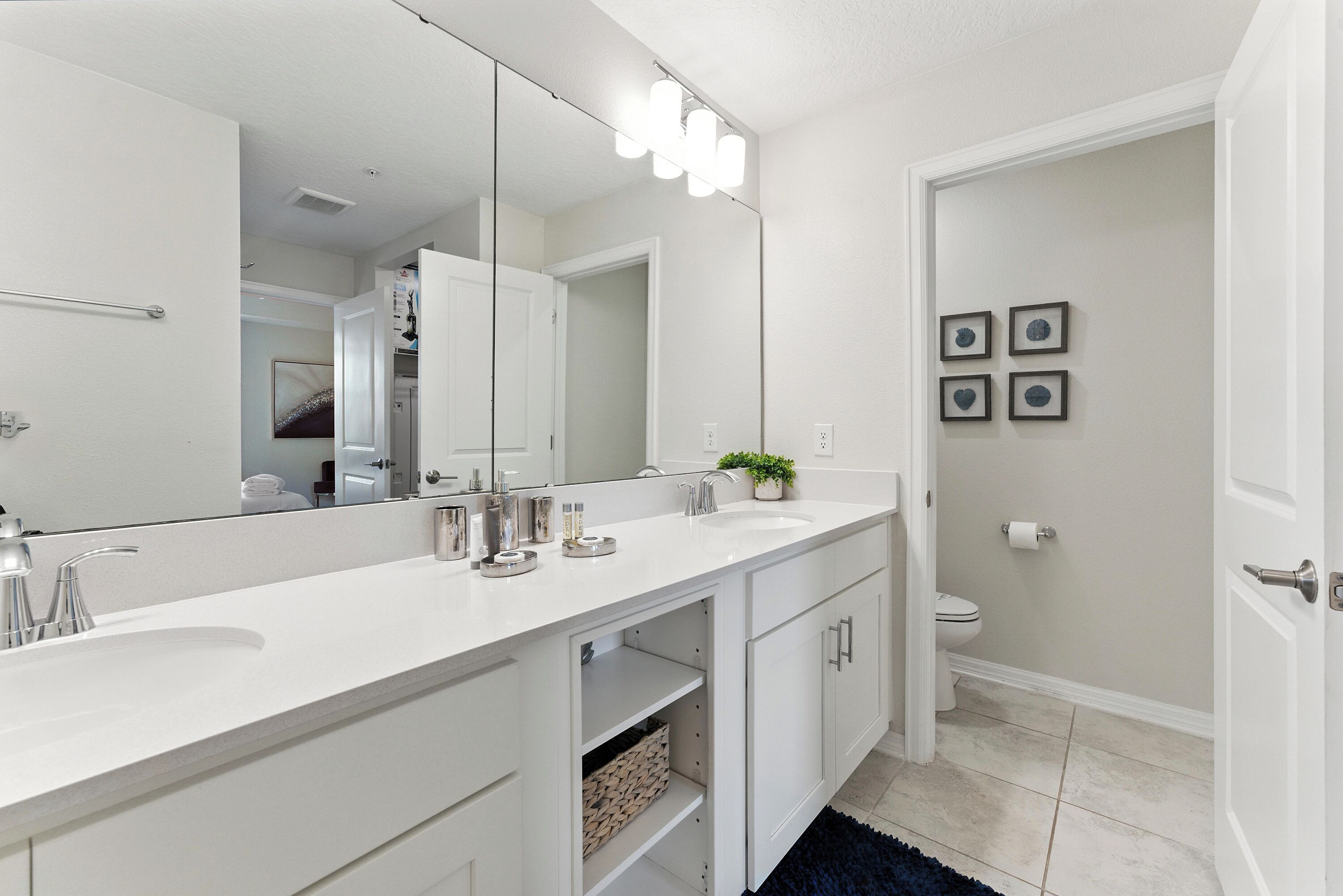 Une salle de bain moderne avec un meuble-lavabo blanc, un grand miroir et des toilettes.