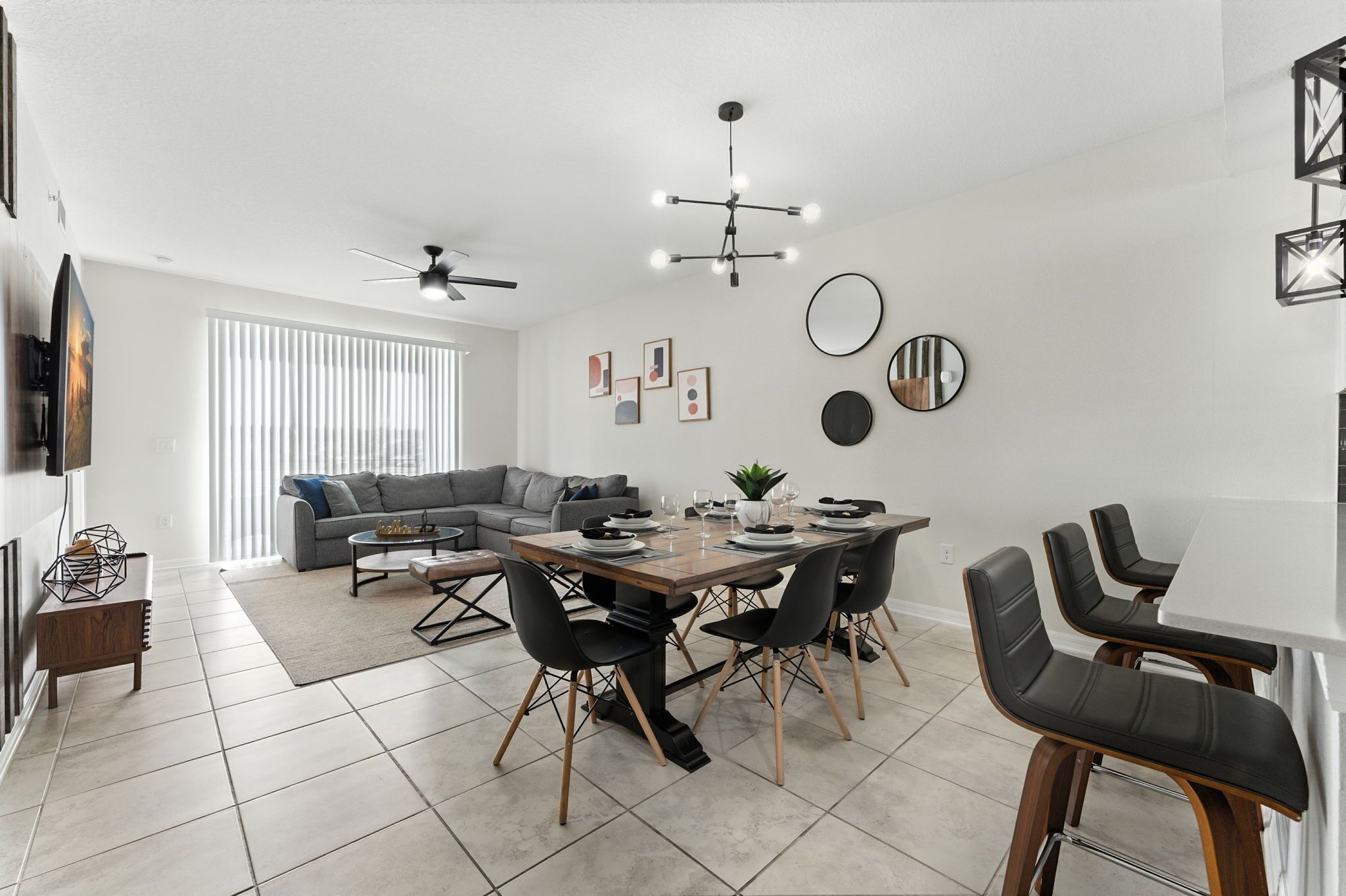 Un espace repas moderne avec une table en bois, des chaises noires et un ventilateur de plafond.