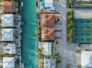 Luchtbeeld van een landgoed aan de kust, met meerdere gebouwen, een jachthaven en een groot groen sportterrein.