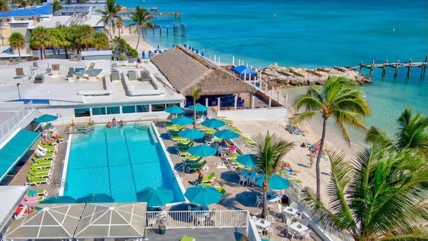Ett semesterhotell med en swimmingpool, solstolar och en strand.