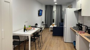 Una cocina compacta con comedor, un pequeño rincón de descanso y un televisor montado en la pared.