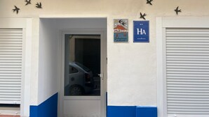 Entrada de garaje con un coche dentro, una puerta y dos carteles en la pared.
