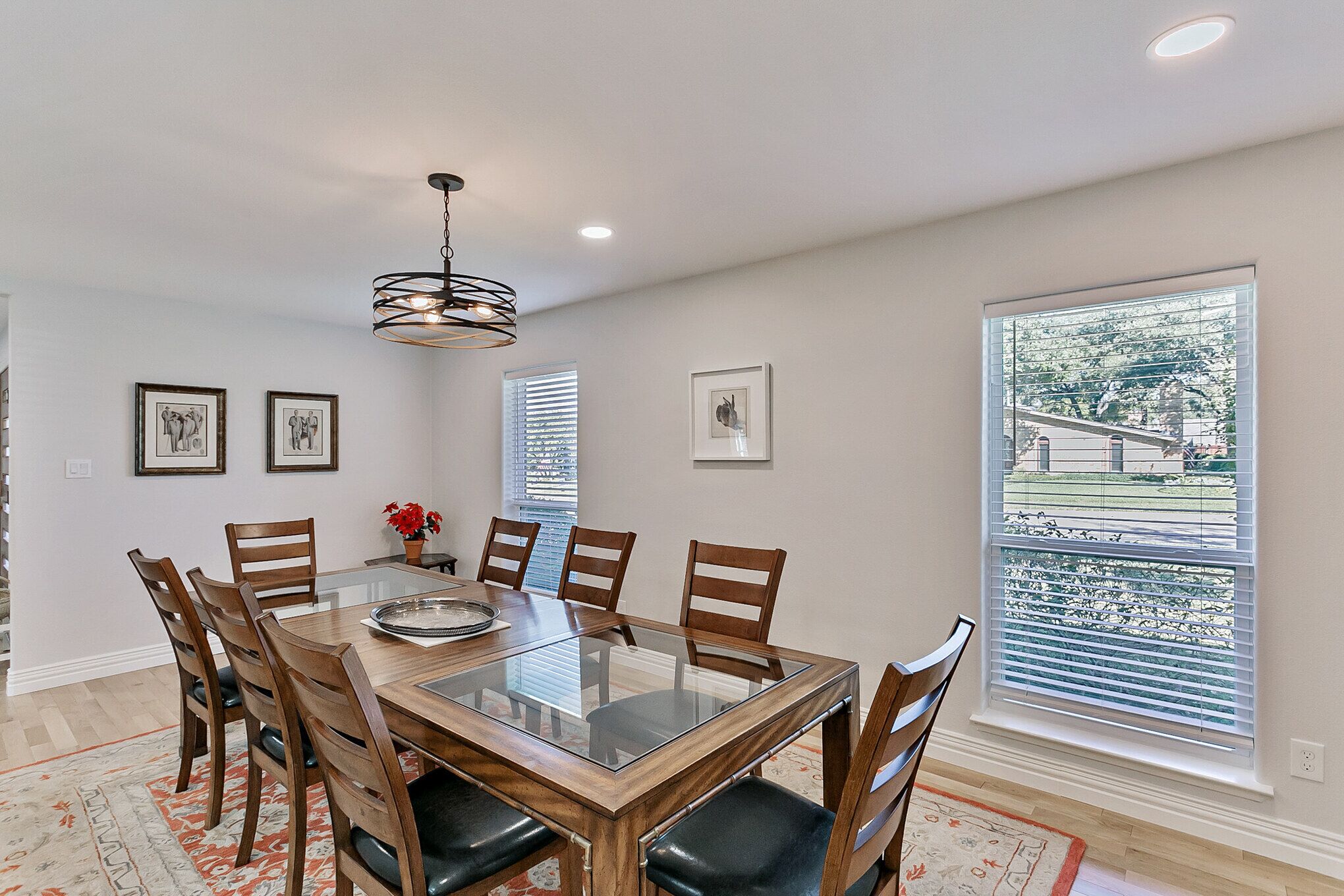 A dining area with a glass-top table, wooden chairs, and a chandelier.
