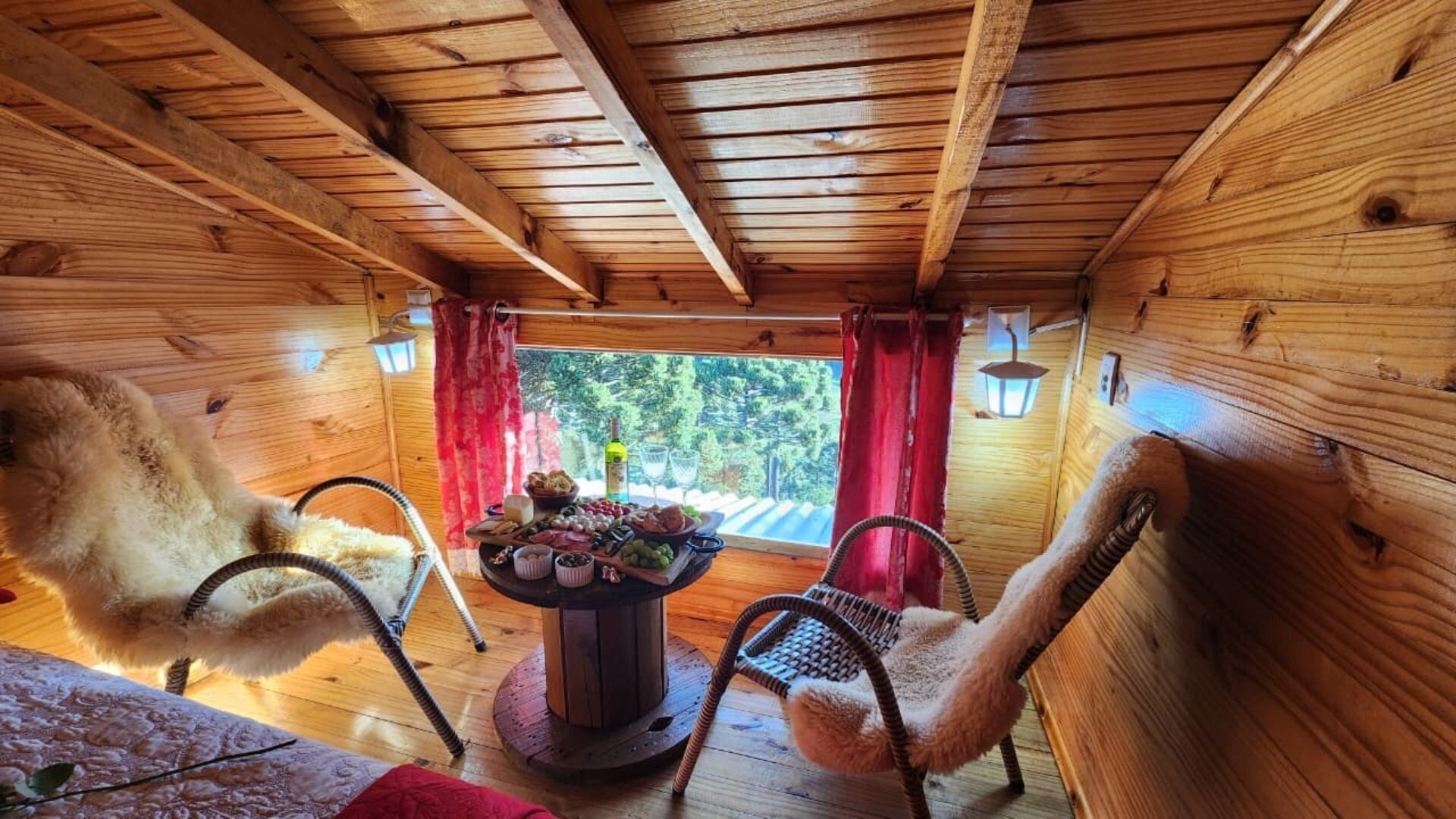 A cozy wooden cabin interior with a dining table set for a meal, surrounded by wicker chairs.
