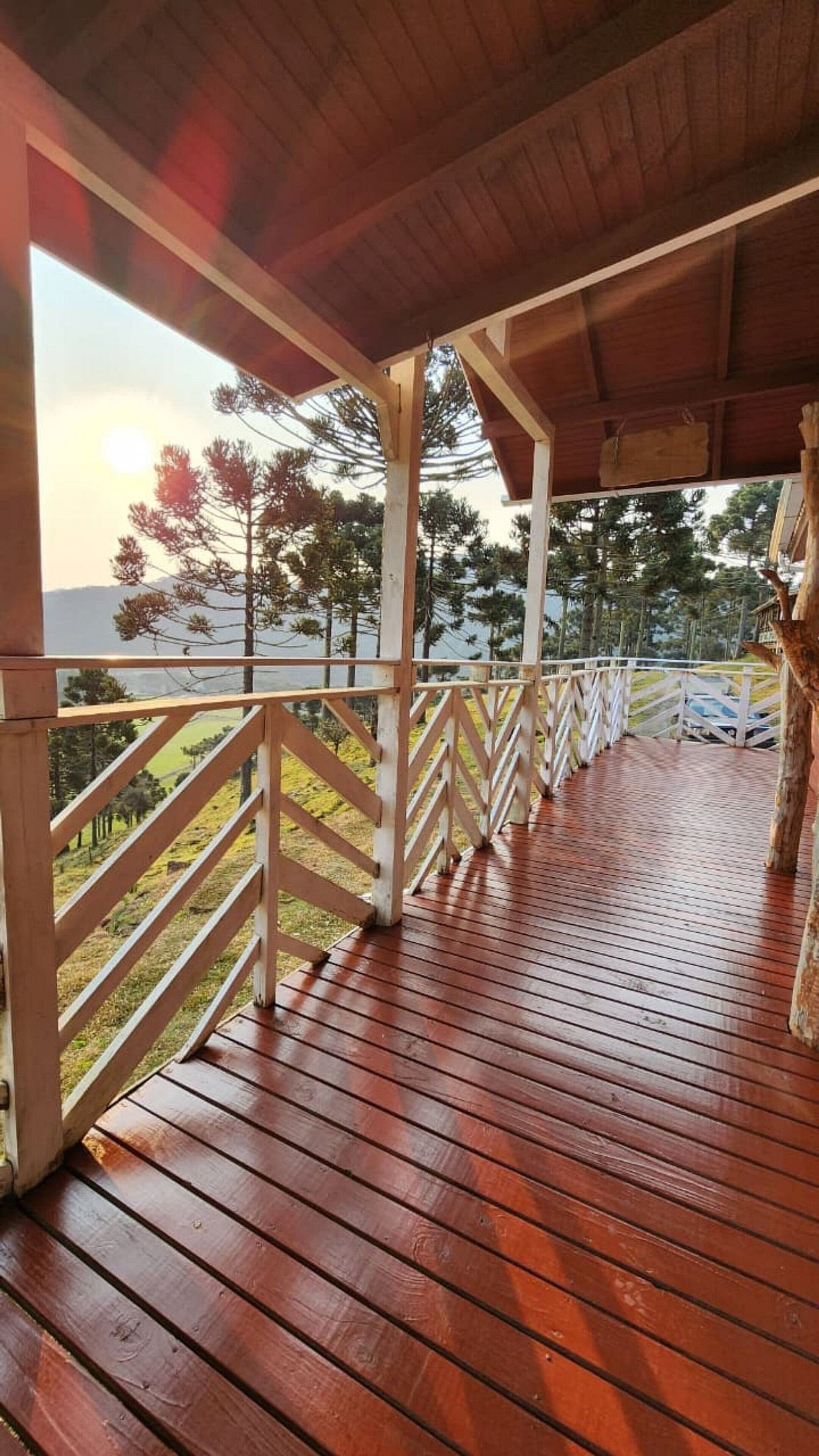 Eine Holzterrasse mit weißer Brüstung, die auf eine Wiese und Bäume blickt.