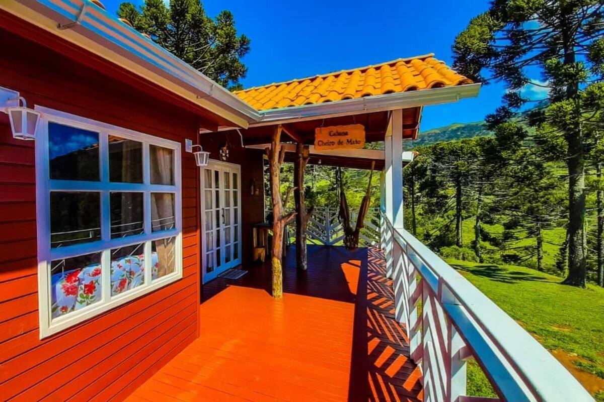 A wooden building with a red exterior, a balcony with a railing, and a sign that reads "Chalet de Mont".