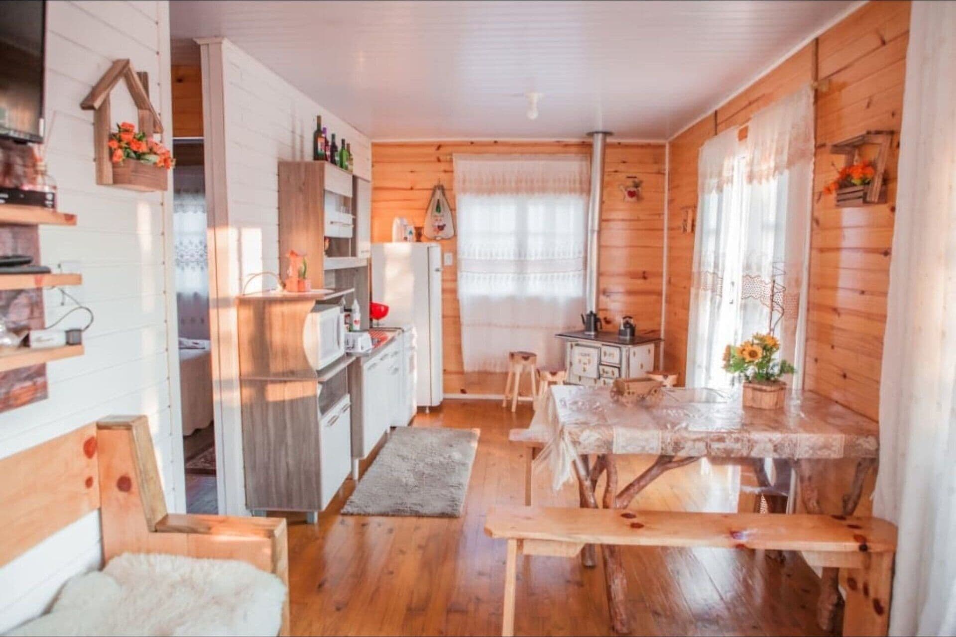 Una cocina acogedora de estilo cabaña con paredes de madera, una mesa de comedor y un banco.