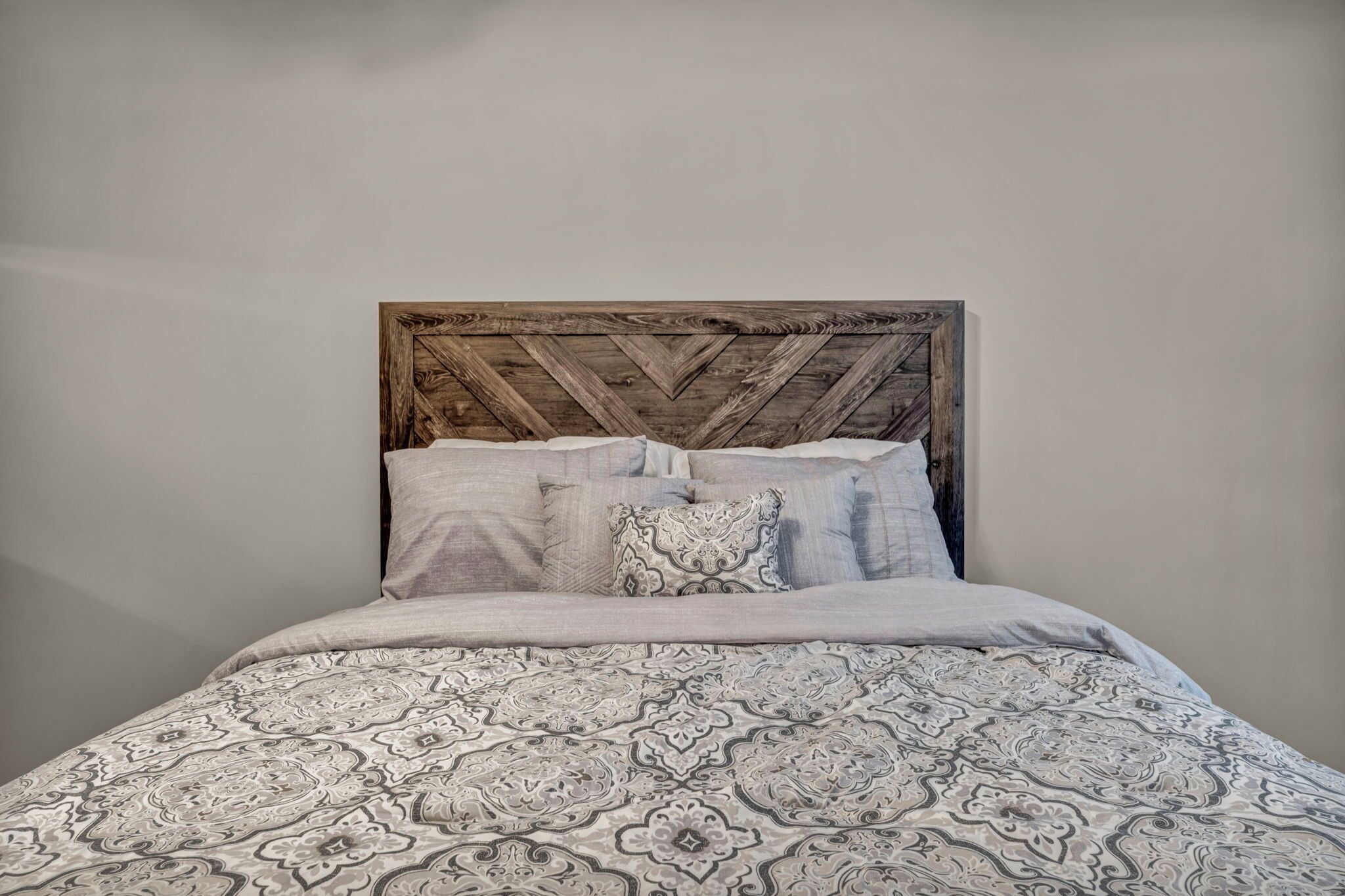 Una cama con colcha estampada y cabecera de madera con diseño en zigzag.