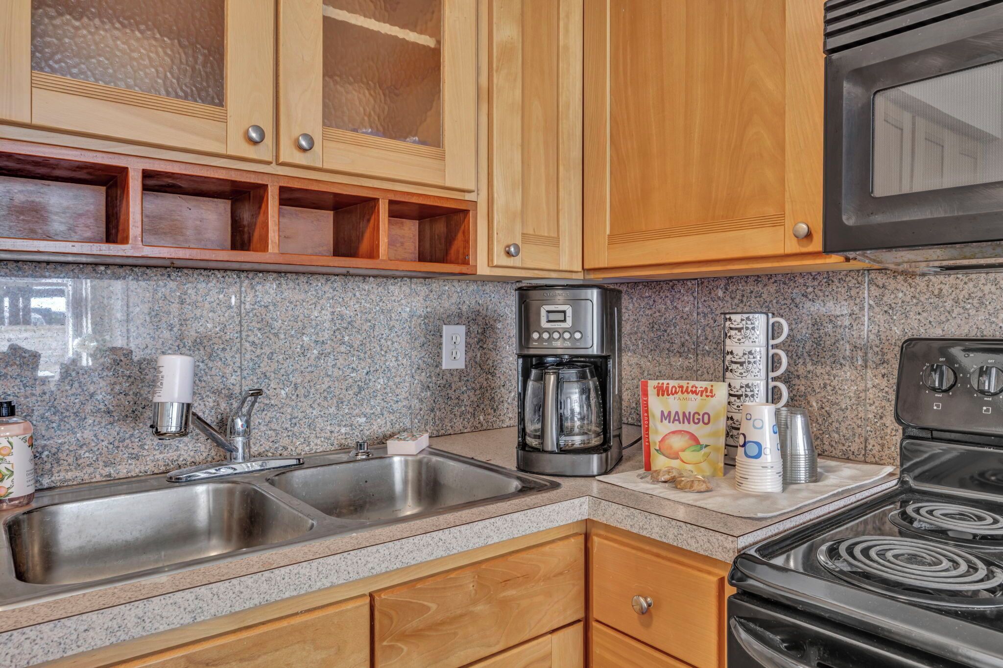 A kitchen with granite countertops, stainless steel appliances, wooden cabinets, and a black stove.