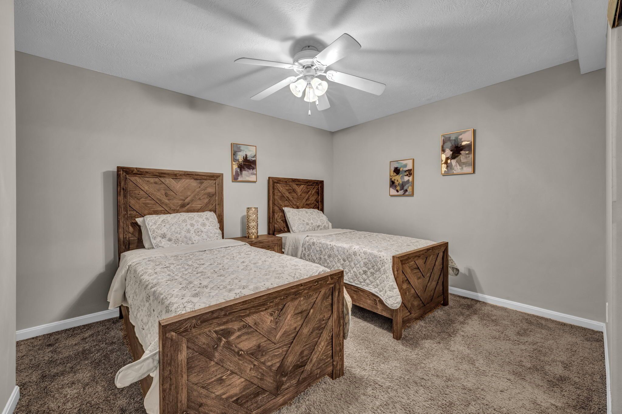 A bedroom with two wooden beds, a ceiling fan, and artwork on the walls.