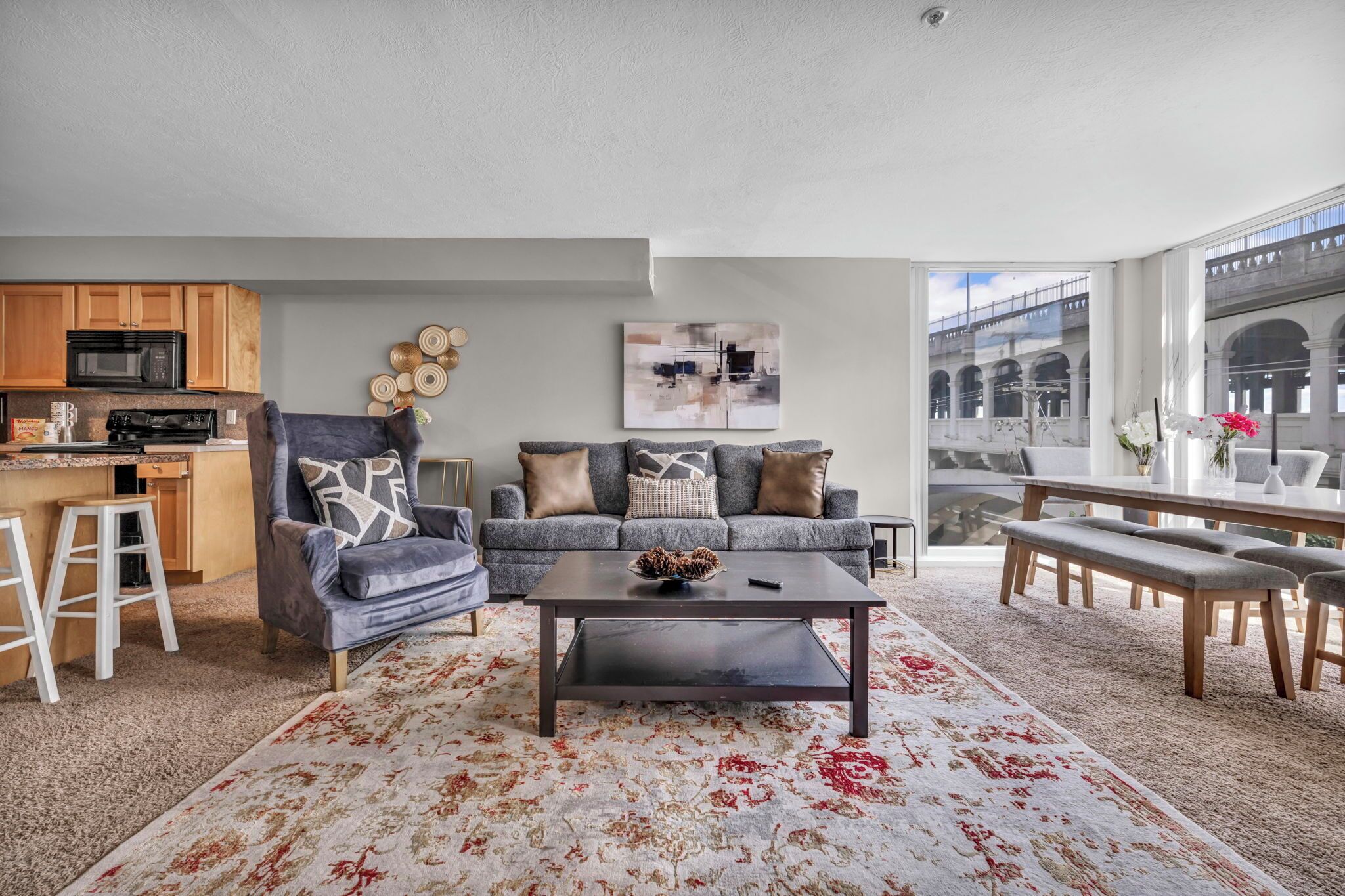 A modern living room with a gray sofa, coffee table, and a view of a bridge through large windows.