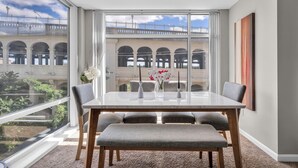 Un coin repas avec une grande fenêtre, une table avec des chaises et un banc.