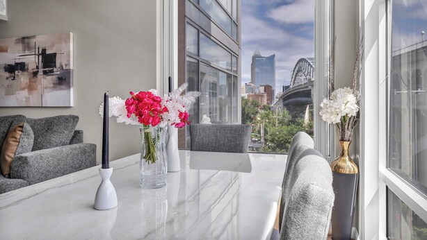 Un espace repas moderne avec une table en marbre, des chaises à revêtement gris et un vase rempli de fleurs.