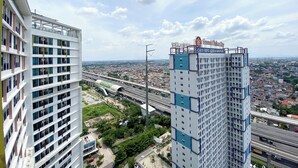 A high-rise building with multiple floors and a prominent sign on top. - White Toned Style Studio At Lrt City Bekasi Apartment (Bekasi)