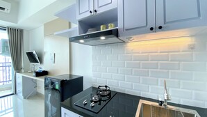 A modern kitchen with white cabinets, a black countertop, and a stainless steel sink. - White Toned Style Studio At Lrt City Bekasi Apartment (Bekasi)