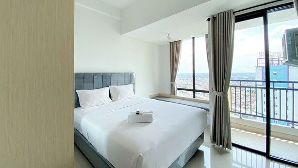 A hotel room with a large bed, a view of the city through a balcony, and a modern design. - White Toned Style Studio At Lrt City Bekasi Apartment (Bekasi)