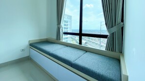 A room with a large window, a built-in bench, and a view of a cityscape. - White Toned Style Studio At Lrt City Bekasi Apartment (Bekasi)