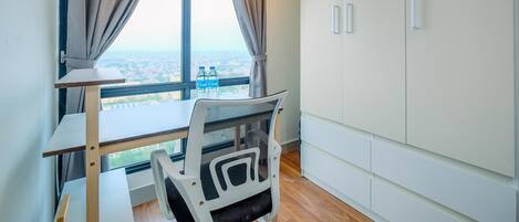 Una habitación moderna con un ventanal grande, un escritorio, una silla y armarios blancos.